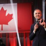 Mark Carney and Diana Carney on stage with the flag of Canada behind them