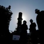 Saudi Aramco engineers walk in front of a gas turbine generator at Khurais oil field east-northeast of Riyadh, Saudi Arabia