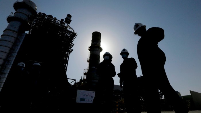 Saudi Aramco engineers walk in front of a gas turbine generator at Khurais oil field east-northeast of Riyadh, Saudi Arabia