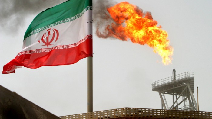 A gas flare on an oil production platform alongside an Iranian flag