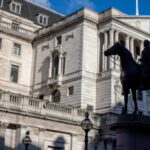 The Bank of England building on Threadneedle Street, London, with its classical architecture and columns under a clear blue sky