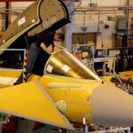 A member of staff works in the cockpit of an aircraft on the Eurofighter Typhoon production line at BAE systems