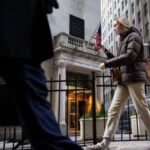 Pedestrians walk past the entrance of the New York Stock Exchange in New York City