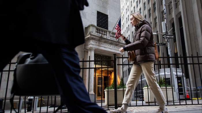 Pedestrians walk past the entrance of the New York Stock Exchange in New York City